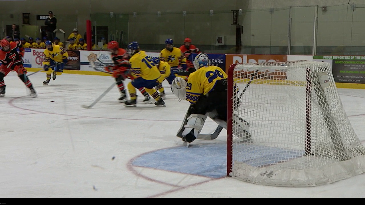 hockey players passing puck in front of goalie