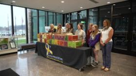 girl scouts and the Mayor of Inver Grove Heights standing in front of boxes of girl scout cookies
